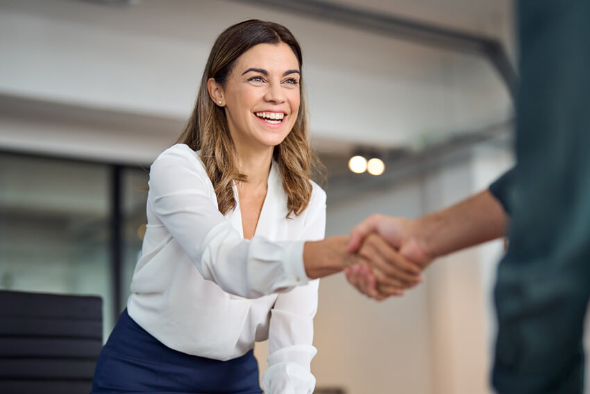 Female job candidate shakes a hiring managers hand at the end of a job interview.
