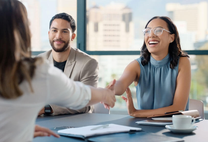 Deux femmes se serrent la main pendant une rencontre avec un client, dédiées à prendre une approche consultative à la dotation en personnel.