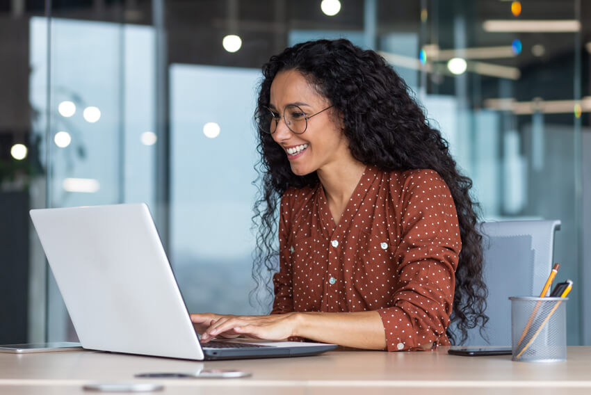 Female with glasses reviewing the February 2025 jobs report on a laptop, looking at January 2025 labor market and economy trends.