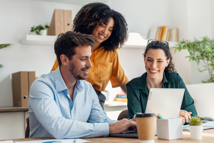 Two female coworkers and one male coworker reviewing the March 2025 jobs report looking at labor market trends in February.